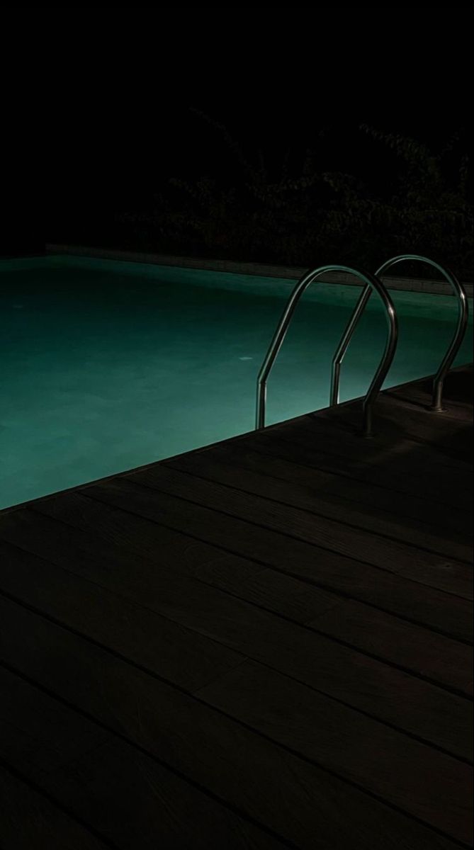 an empty swimming pool at night with no one in the water or onlookers