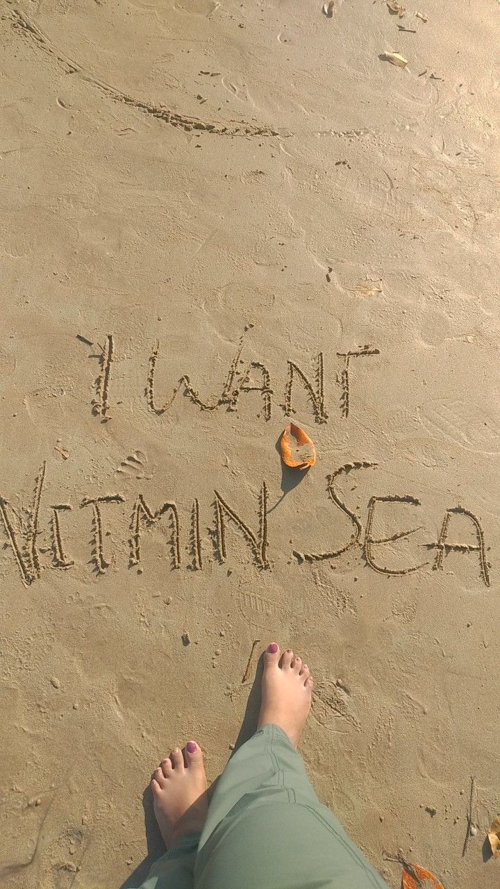 someone is writing i want vitamin sea in the sand with their feet on the beach