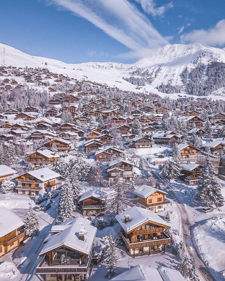 an aerial view of a ski resort in the mountains with snow on the ground and trees