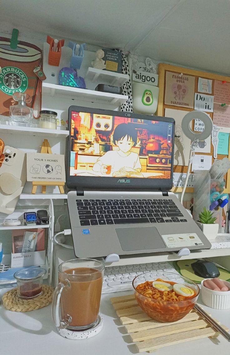 an open laptop computer sitting on top of a white desk next to a bowl of food