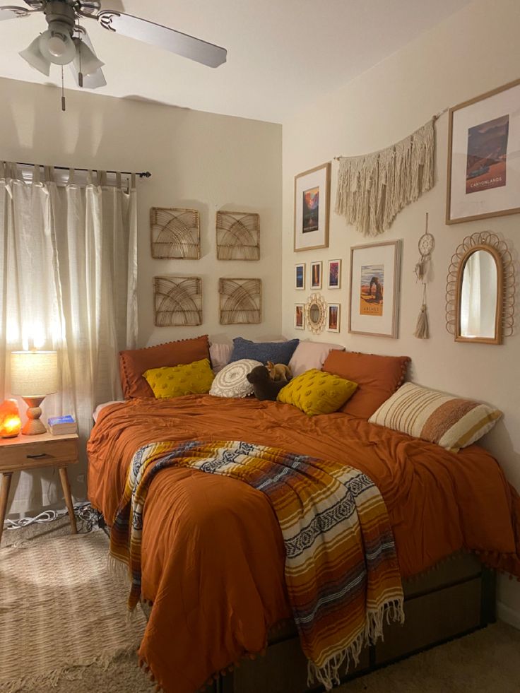 a bedroom with orange bedding and pictures on the wall