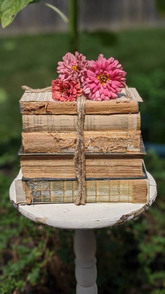 a stack of books sitting on top of a white table next to a pink flower