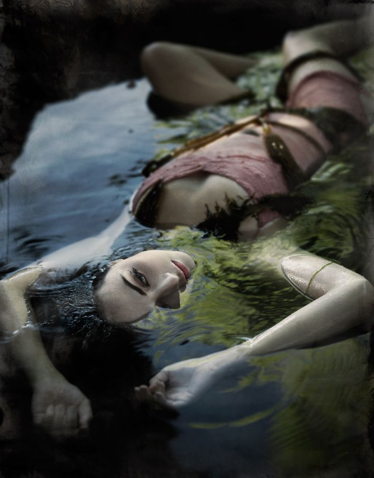 black and white photograph of a woman laying in the water with her head down on another woman's back