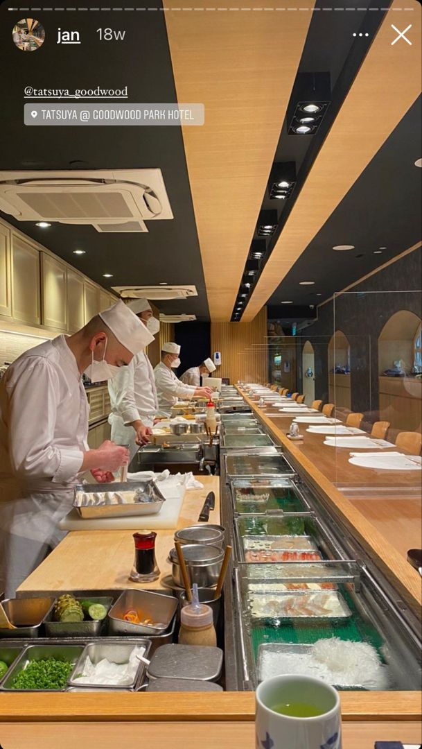 two chefs preparing food in a restaurant kitchen with an iphone app on the wall above them