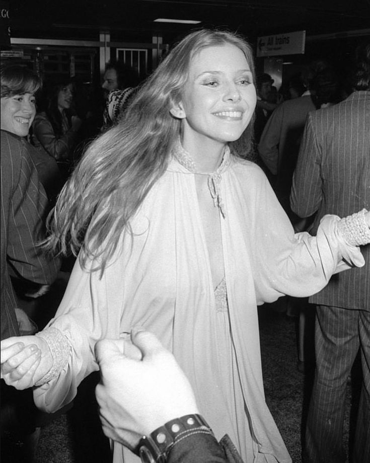 a black and white photo of a woman holding something in her hand while standing next to a man