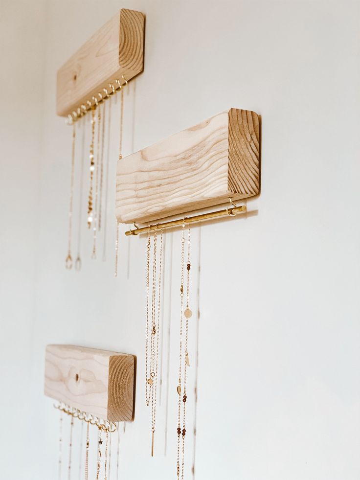 three wooden pieces with chains hanging from them and some beads attached to the strings on the wall