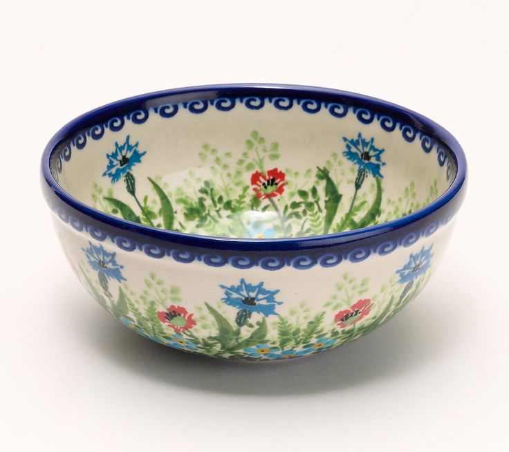 a blue and white bowl with flowers painted on the side, sitting in front of a white background