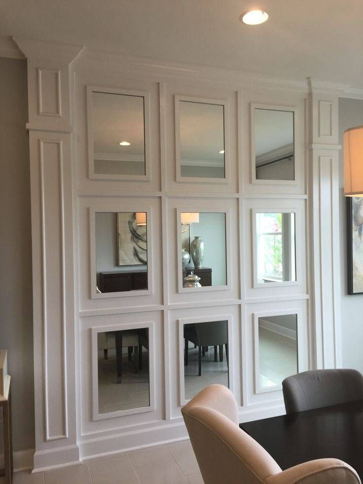 a dining room table and chairs in front of a wall with mirrors on the walls