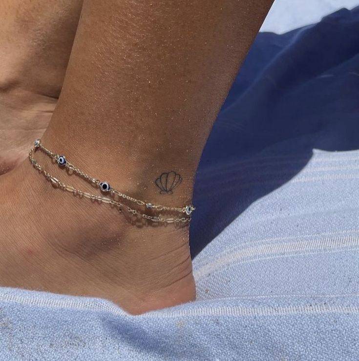 a woman's foot with a tattoo on it and a chain around the ankle