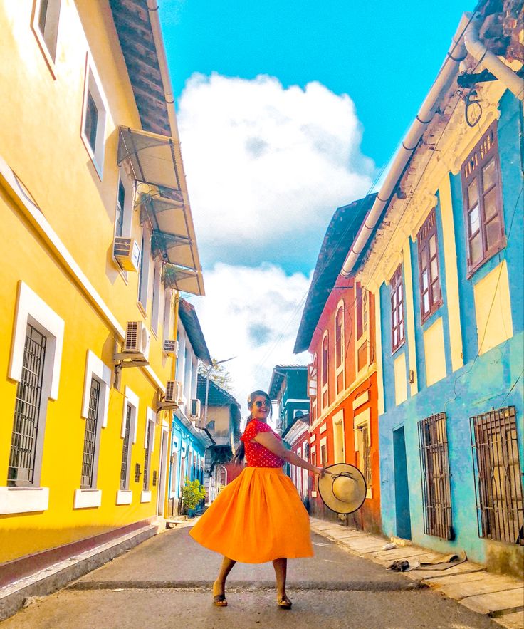 a woman in an orange and red dress is walking down the street by some buildings