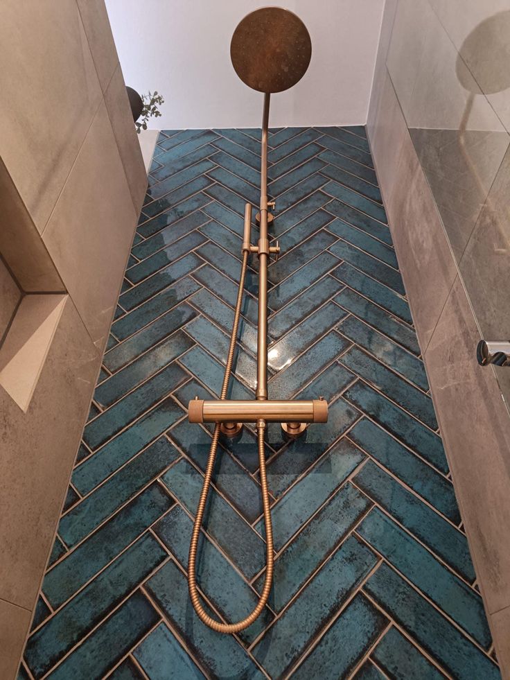 a shower head in the middle of a bathroom with blue tiles on the floor and walls