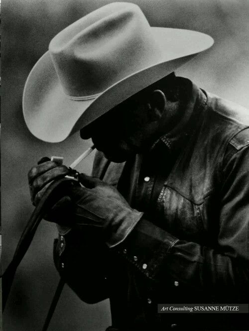 a black and white photo of a man wearing a cowboy hat