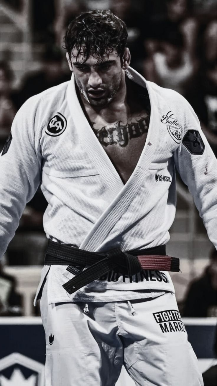 a man standing in front of a crowd wearing a white uniform and holding a black belt