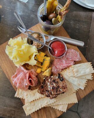 a wooden cutting board topped with different types of appetizers and condiments