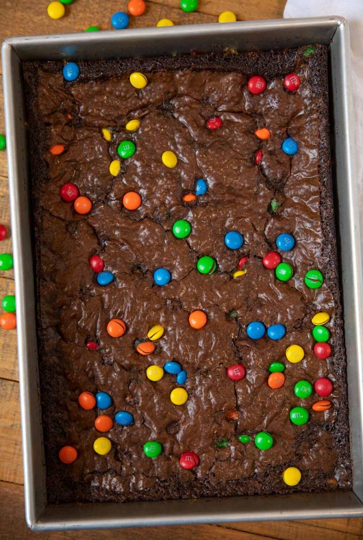 a cookie cake with chocolate frosting and m & m candies in it on a wooden table