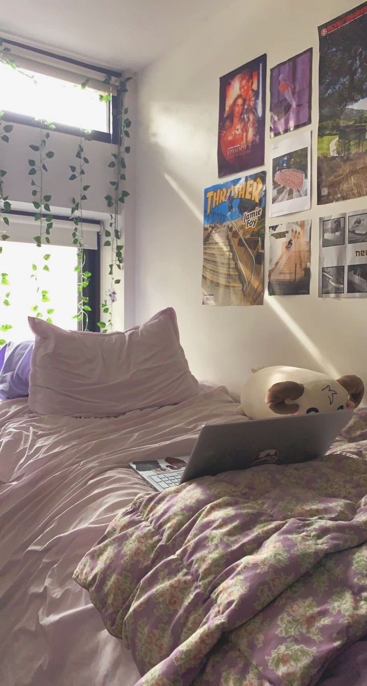 a laptop computer sitting on top of a bed in a room with posters above it