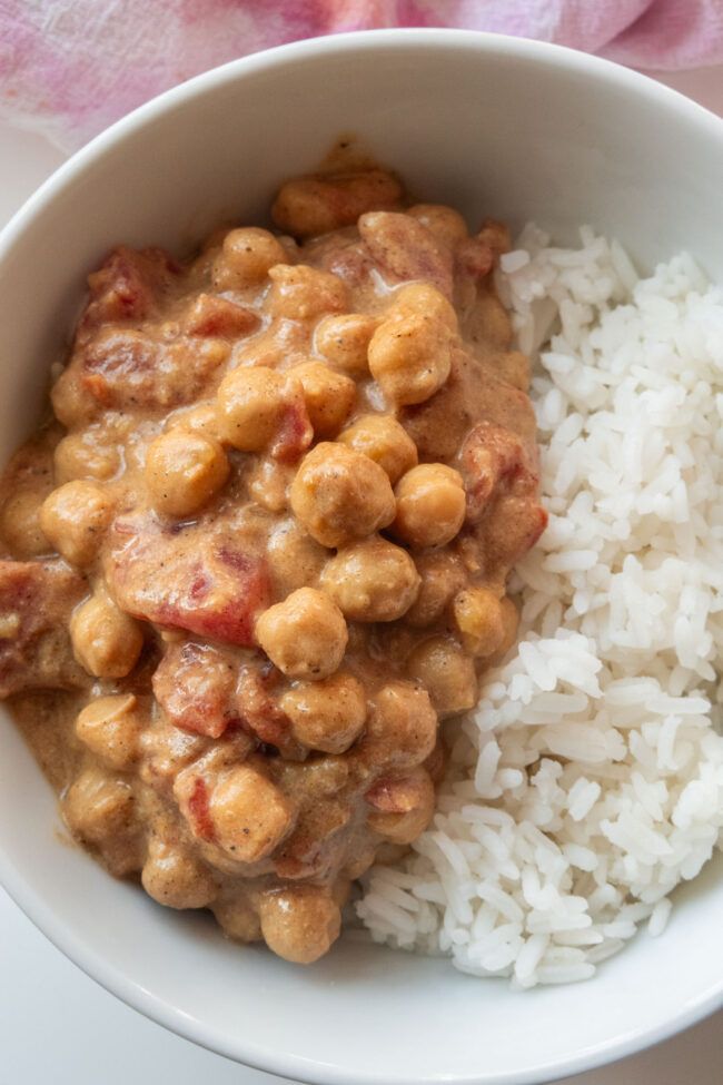 a white bowl filled with rice and beans next to a pink towel on top of a table