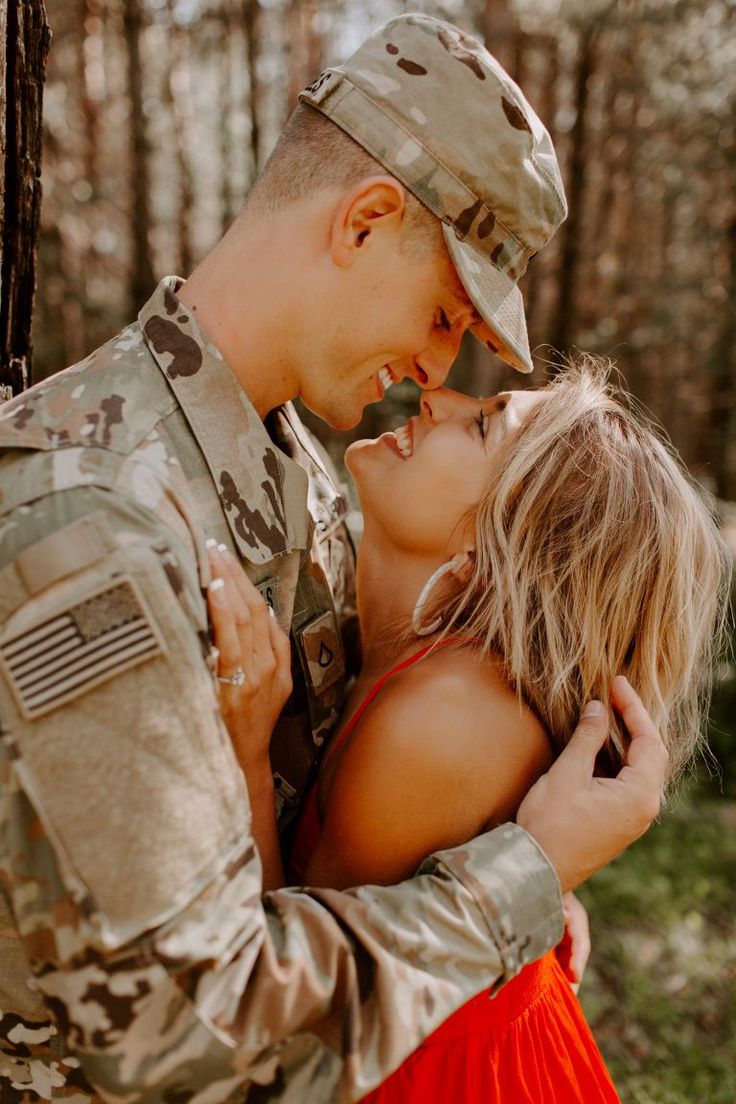 a soldier is hugging a beautiful blonde girl in the woods while she kisses her forehead