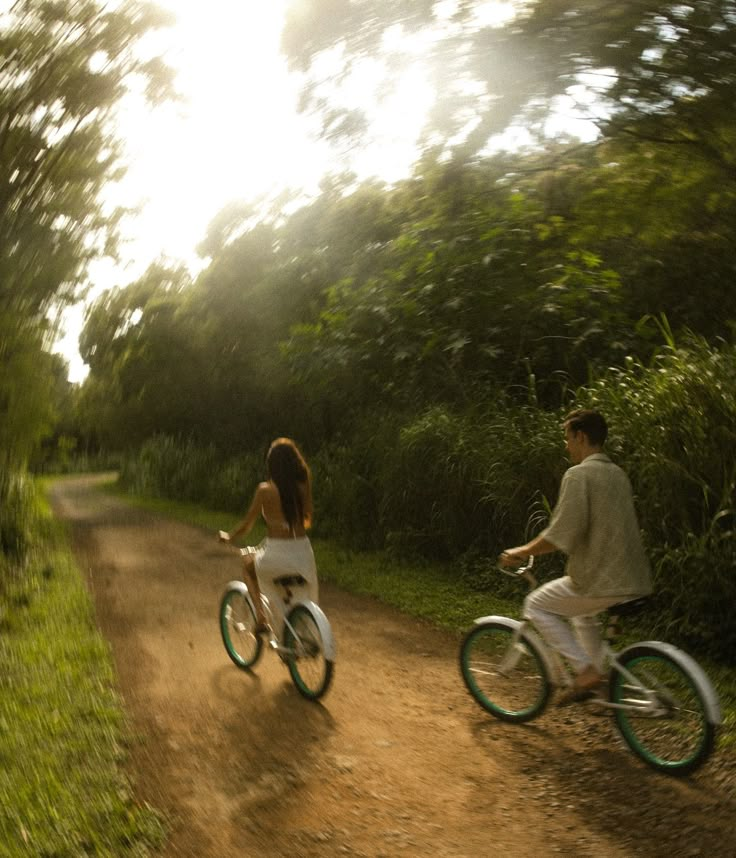 two people riding bikes down a dirt road