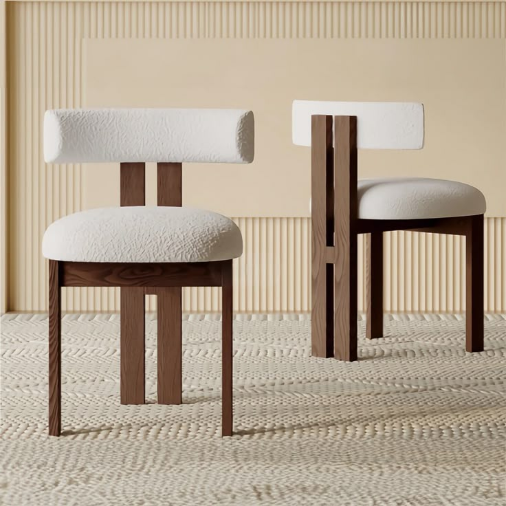 two wooden chairs with white upholstered cushions in front of a beige striped wall