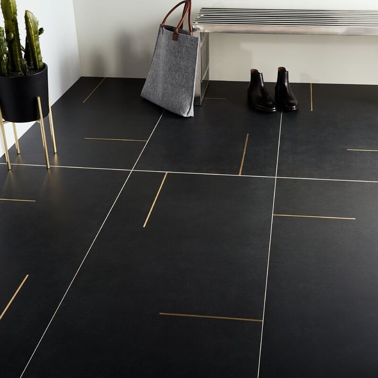 a black tile floor with gold lines on it and a bag next to the bench