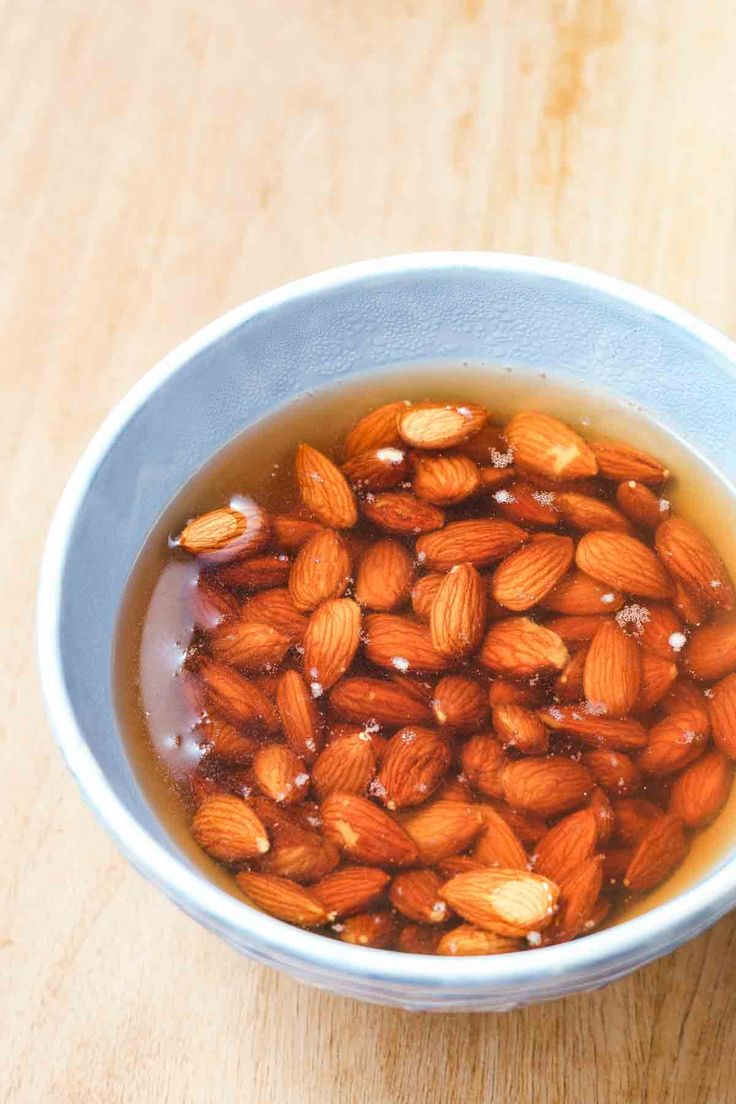 a bowl filled with almonds sitting on top of a wooden table