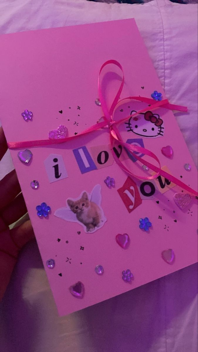 a hand holding a pink greeting card with hello kitty on it, and the words i love you