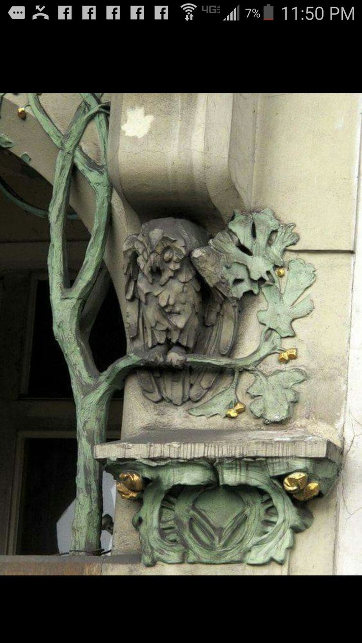 a statue on the side of a building next to a tree