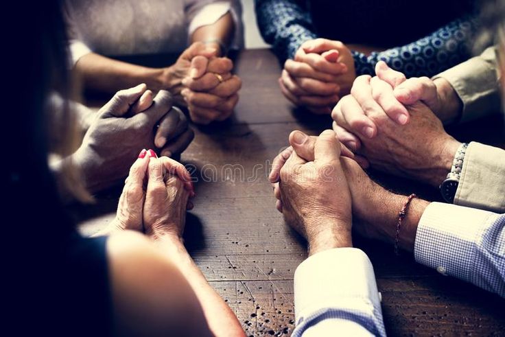 several people sitting at a table with their hands together