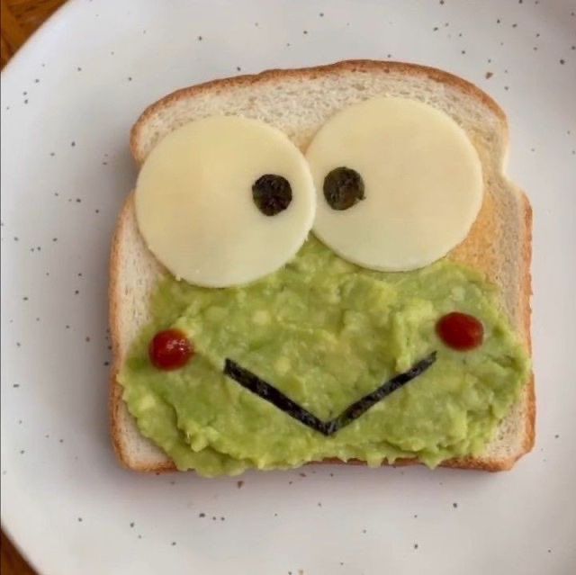 a piece of bread with an image of a frog made out of avocado on it