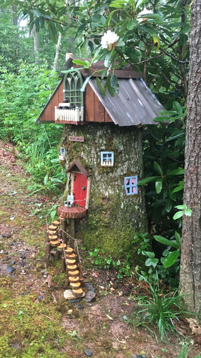 a tree house in the woods with stairs leading up to it's door and windows