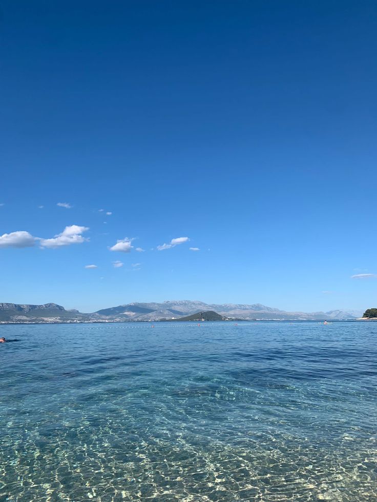 clear blue water with mountains in the distance