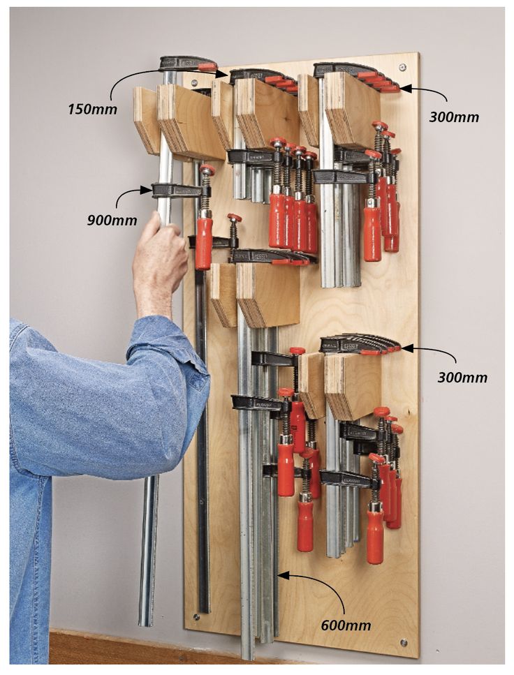 a man is working on a wall mounted tool rack with drill holes and screwdrivers