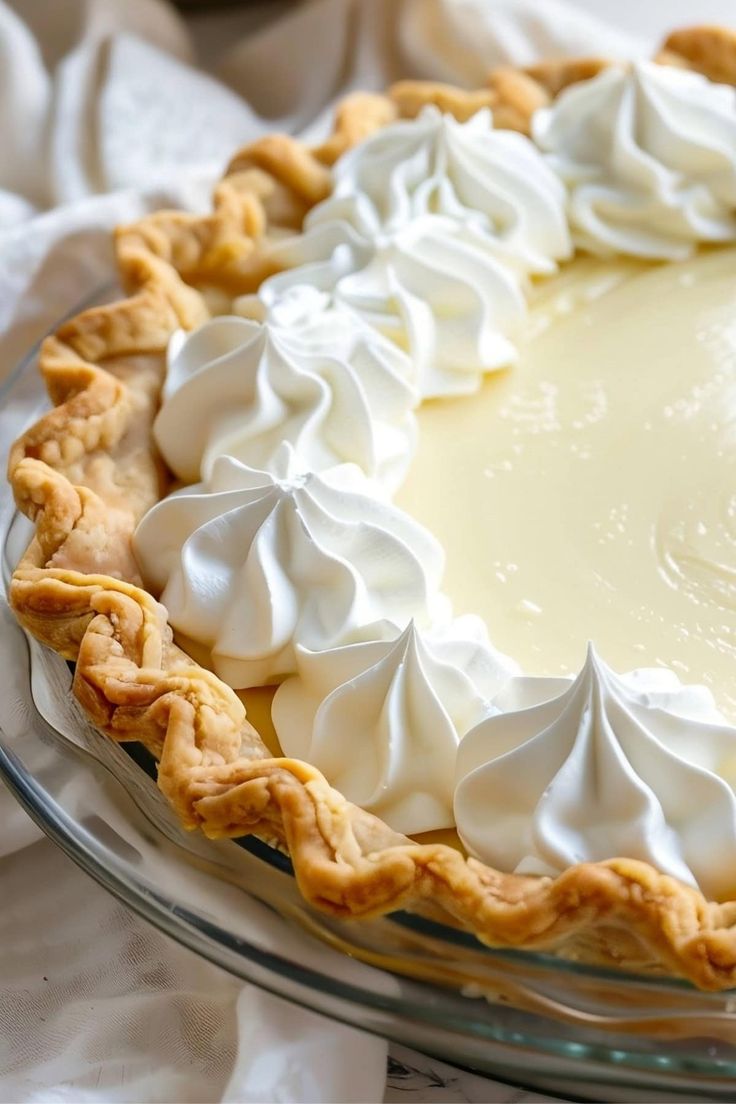 a pie with whipped cream on top is sitting on a glass platter, ready to be eaten