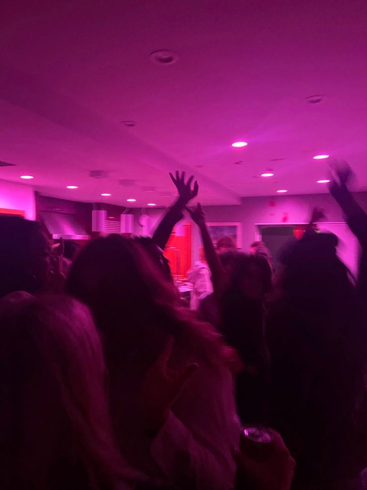 a group of people standing in a room with their hands up to the ceiling and lights on