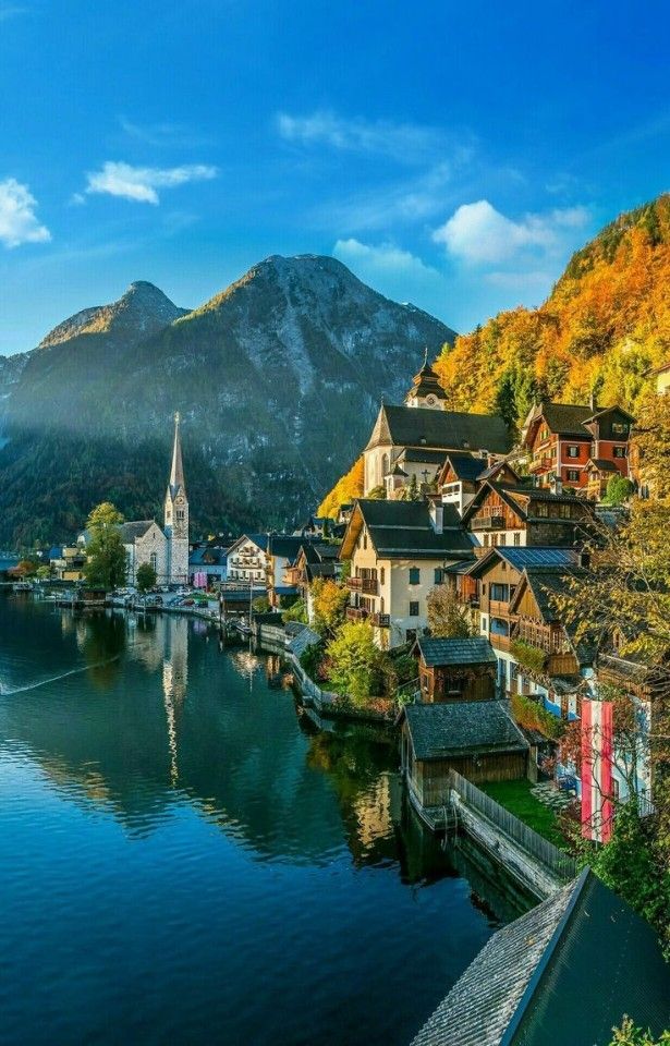 a lake with houses and mountains in the background