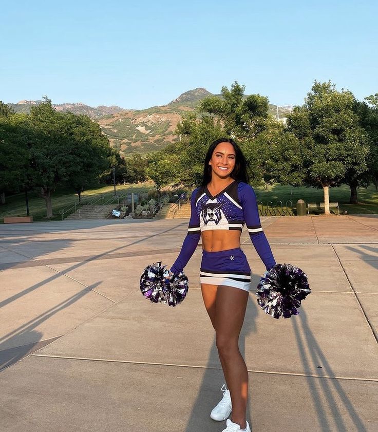 a cheerleader is posing for the camera with her pom poms in hand