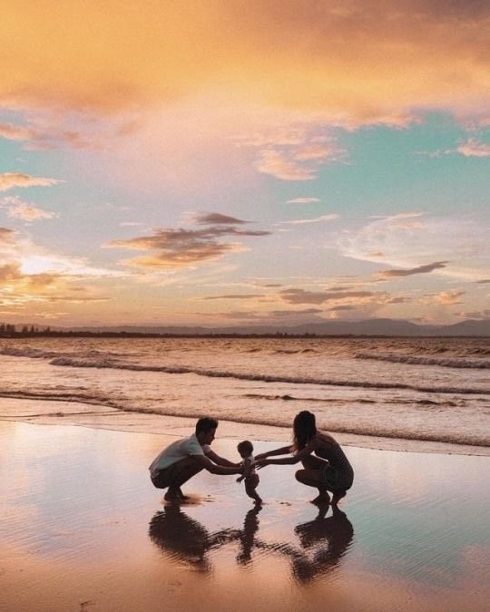 two people holding hands on the beach at sunset