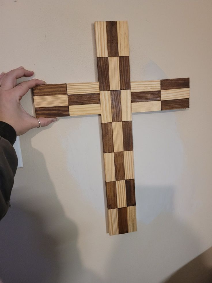 a person holding a wooden cross on the wall