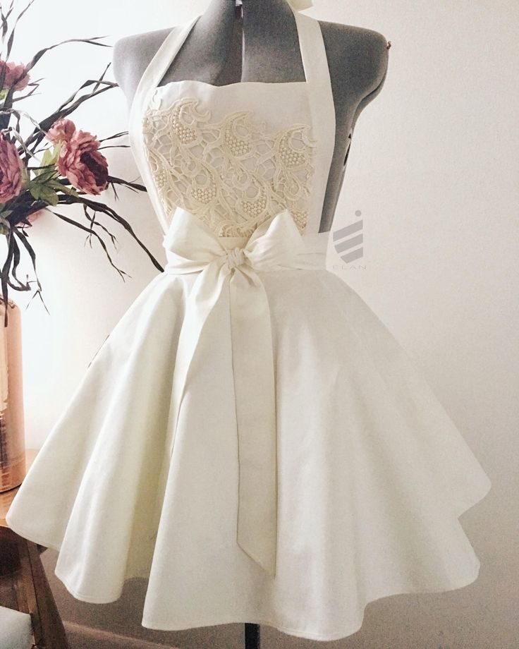 a dress on a mannequin next to a vase with flowers and a bouquet