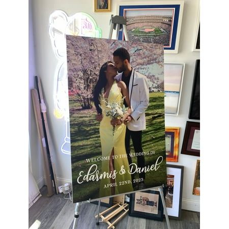 a couple kissing in front of a wedding sign