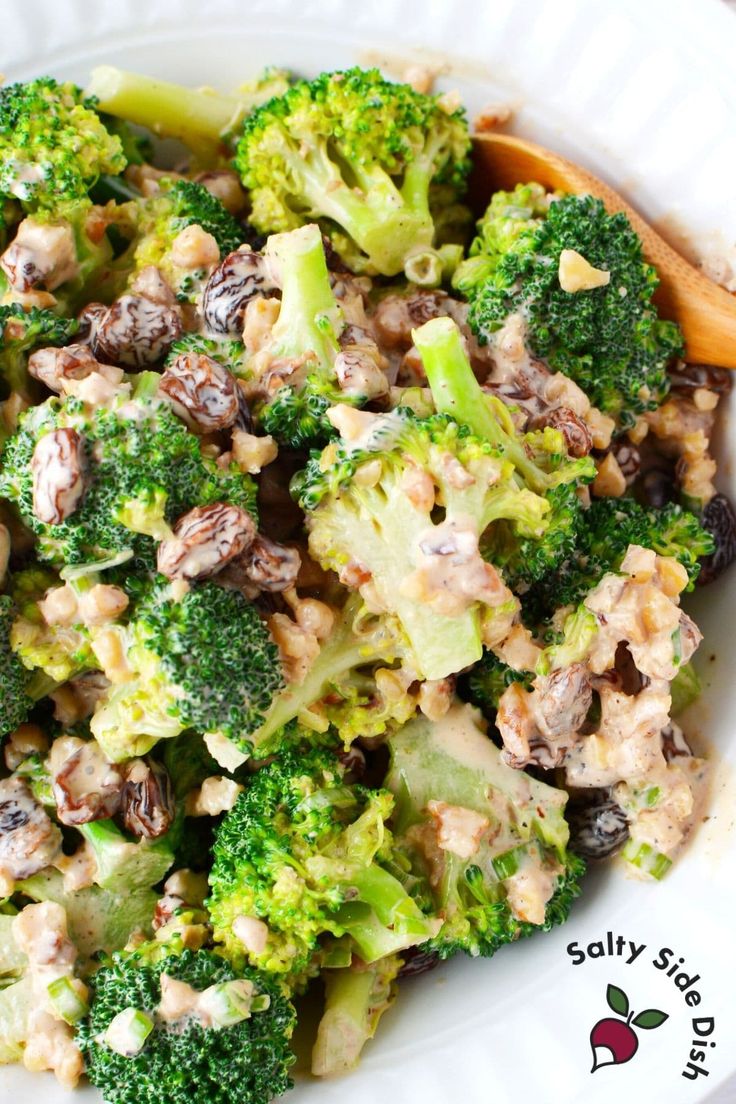 a white bowl filled with broccoli and other food on top of a table