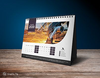 a desk calendar with an image of a man working on a piece of machinery in the background