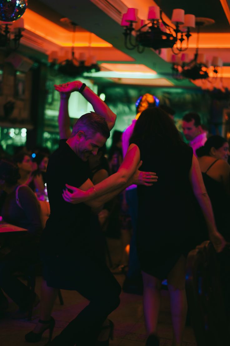 two people dancing at a party in the dark