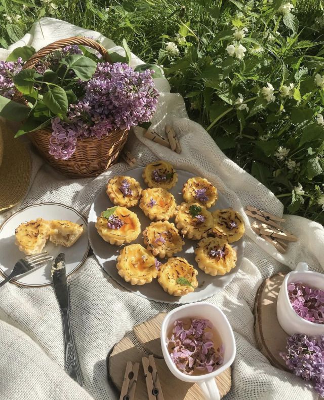 some food is sitting on a table with purple flowers and silverware in the foreground