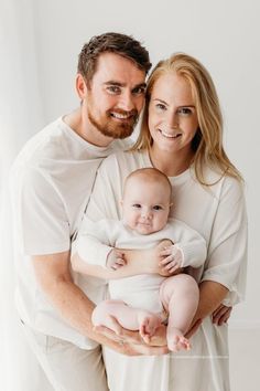 a man and woman holding a baby in their arms