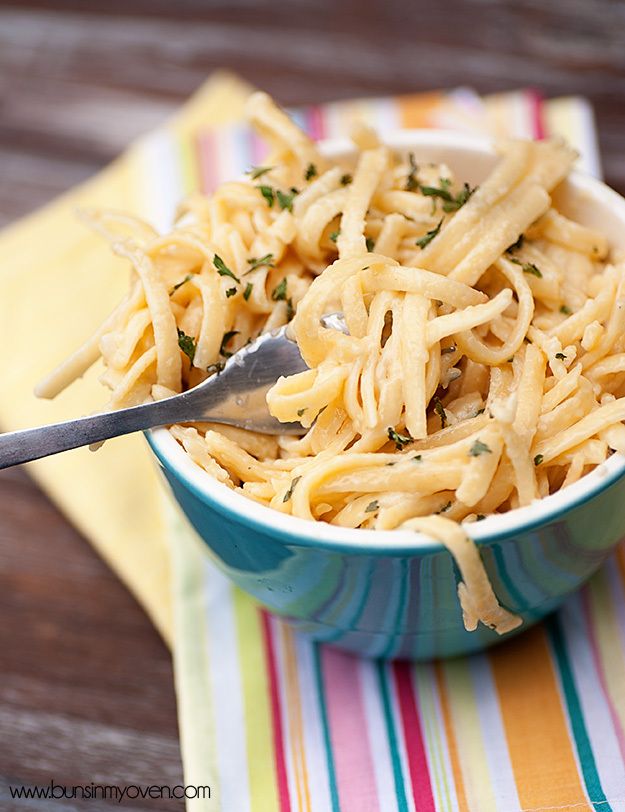 a blue bowl filled with pasta on top of a striped table cloth next to a fork