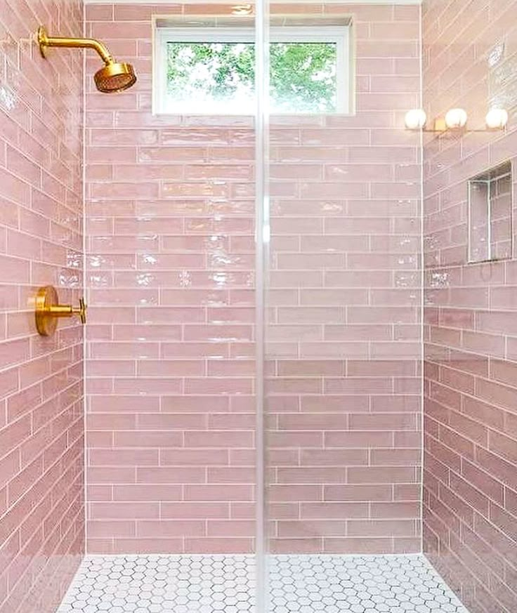 a pink tiled shower with gold fixtures and white tile flooring is shown in this bathroom