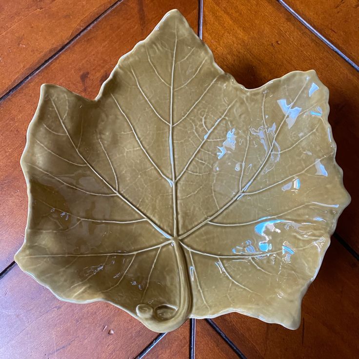 a green leaf shaped bowl sitting on top of a wooden floor