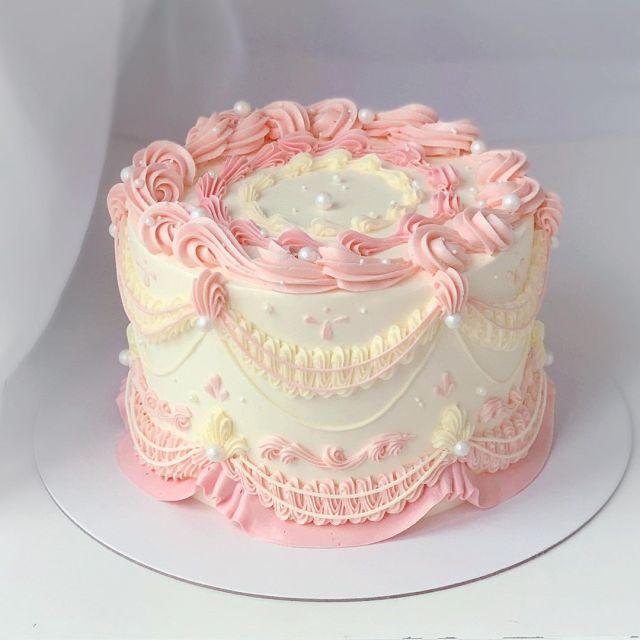 a pink and white decorated cake on a plate